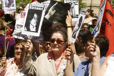 Chileans opposed to former dictator Augusto Pinochet hold posters of relatives who disappeared during his government, as several thousand protesters gathered to celebrate his death in downtown Santiago, December 12, 2006.