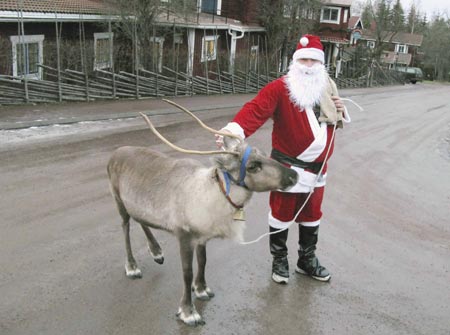 A man dressed as Santa Claus walks his pet reindeer as he visit hotels and shops in Tallberg December 24, 2006. 