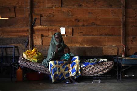 A Somali refugee woman sits with her sick baby on a bed inside a paediatric section of a hospital in Ifo camp near Dadaab, about 80km (50 miles) from Liboi on the border with Somalia in north-eastern Kenya, January 8, 2007. Aid agencies are operating three large refugee camps in Dadaab where about 160,000 Somali refugees are held and said they could provide more staff to help Kenya with any new influx.