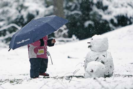 A young girl looks at a snowman made by her father in Vancouver's Stanley Park January 10, 2007. The 14th storm in the last couple months blew into the lower mainland area of Canada's west coast packing strong winds followed by snow and cold temperatures.