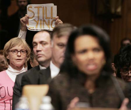 An anti Iraq war protester holds a sign while U.S. Secretary of State Condoleezza Rice (R) testifies before the Senate Foreign Relations Committee on Capitol Hill in Washington, January 11, 2007.