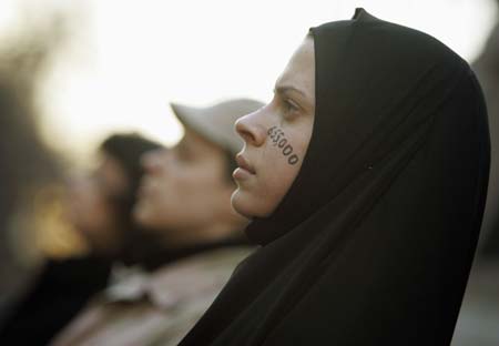 Alicia Casilio, dressed as an Iraqi civilian, stands silently at an anti-Iraq war protest in Boston, Massachusetts January 11, 2007. The numbers on Casilio's face represent the estimated number of Iraqi civilians killed in the war. 