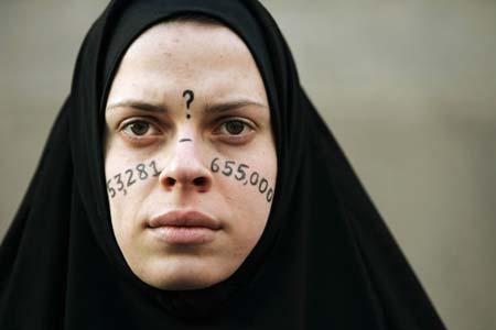 Alicia Casilio, dressed as an Iraqi civilian, stands silently at an anti-Iraq war protest in Boston, Massachusetts January 11, 2007. The numbers on Casilio's face represent the estimated number of Iraqi civilians killed in the war. 