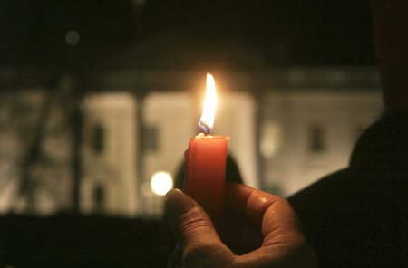 A protester holds a candle with the White House in the background during an anti-war rally and candlelight vigil in Washington January 11, 2007. Anti-war activists took to the streets of U.S. cities on Thursday for the first of what organizers promised would be thousands of protests against President George W. Bush's plan to send more U.S. troops to Iraq. 