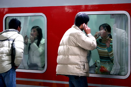Two girls on a train say good-bye to their friends at a railway station in East China's Jiangsu Province, January 12, 2006. [Gu Wei/Modern Express]