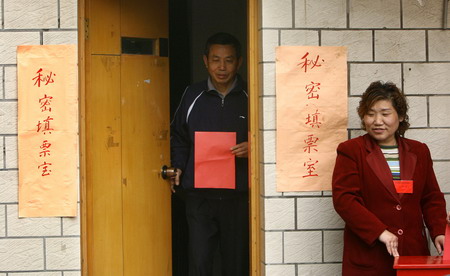 .A man holding a ballot leaves a room as a women waits to collect his ballot in a Nanjing community in East China's Jiangsu Province, April 11, 2006. Voters need to privately fill out the ballot in a separate room during the Resident Committee election. [Yang Bo/Modern Express]