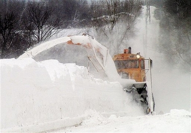 A 1952 Oshkosh tractor powers a snow blower to cut back snow banks on a road Friday, Feb. 9, 2007, in Scriba, N.Y. While the northern Plains and Northeast shiver in dangerously cold temperatures, the folks in upstate New York are keeping warm shoveling snow, lots of snow. (AP