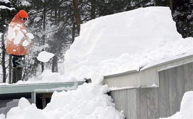 Bob Munger clears snow from the roof of his mother's home in Mexico, N.Y., Friday, Feb. 9, 2007. Nearly 100 inches (254 centimeters) of snow have buried Oswego county, with more on the way, and the governor has declared a disaster. More than a week of bitter cold and icy roads have caused at least 20 deaths across the northern quarter of the United States, but winter is most clearly on display in Oswego County, with some areas getting up to 3 inches (7 centimeters) of snow an hour Thursday night. (AP