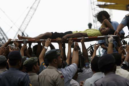 Indonesian policemen and soldiers carry an injured man evacuated from the ferry that caught fire at the Tanjung Priok port in Jakarta February 22, 2007.