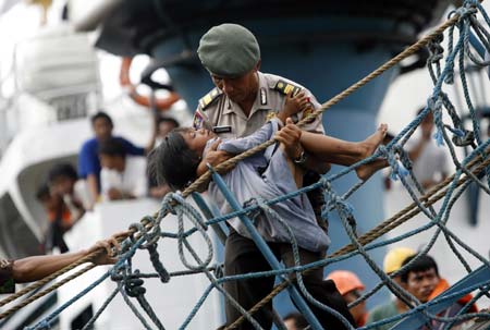 An Indonesian policeman carries an injured young girl off a ferry that caught fire, at the Tanjung Priok port in Jakarta February 22, 2007.