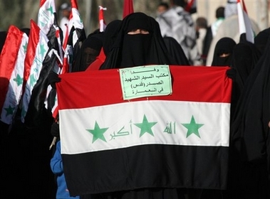 A Shiite woman, follower of radical anti-US cleric Muqtada al-Sadr holds an Iraqi flag and a note reading 'Delegation from martyr office of al-Sadr from Amarah city', during a march through the holy city of Najaf, Iraq, Monday, April 9, 2007, on the fourth anniversary of the fall of Baghdad to the US forces. Tens of thousands draped themselves in Iraqi flags and marched through the streets of two Shiite holy cities Najaf and Kufa in a rally that was called for by al-Sadr who issued a statement ordering his militiamen to redouble their battle to oust American forces and argued that Iraq's army and police should join him in defeating 'your archenemy.'
