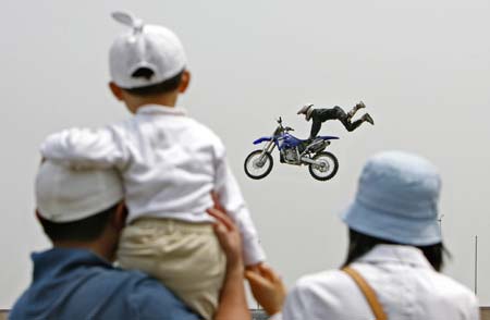 Spectators watch Rhys Hillier of Australia as he jumps with his motorcycle during a demonstration performance on the opening day of Asia Extreme Games in Shanghai May 3, 2007.