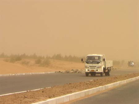 A truck travels slowly during a sandstorm on a highway in Tongliao, North China's Inner Mongolia Autonomous Region, May 7, 2007. The sandstorm reduced the visibility less than 50 meters, Xinhua reported. [Xinhua]