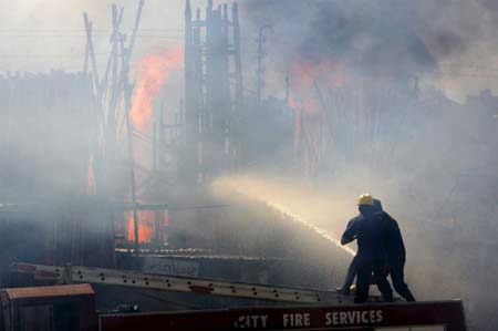 Firefighters try to put out a fire at a shop during protests in Karachi May 13, 2007. A Pakistani opposition supporter was killed in Karachi on Sunday during a protest against violence the previous day in which 34 people were killed in clashes between pro-government and opposition activists. 