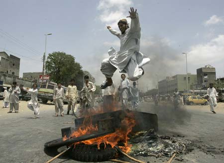 A protester jumps over a bonfire during demonstrations in Karachi May 13, 2007. A Pakistani opposition supporter was killed in Karachi on Sunday during a protest against violence the previous day in which 34 people were killed in clashes between pro-government and opposition activists.