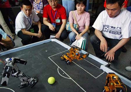 Students and designers for the Harbin Institute of Technology Robot Soccer Team watch a match in Wuhan, Central China's Hubei Province, May 14, 2007. The 8th National Robot Soccer Competition recently kicked off in the city, attracting 86 teams from across the country. The winners will represent China at the Federation of International Robot-soccer Association World Cup in San Francisco on June 13. [newsphoto]