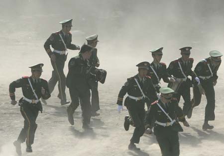 Paramilitary policemen cover their faces during a dust storm during an exercise break at an army base in Beijing May 16, 2007. 