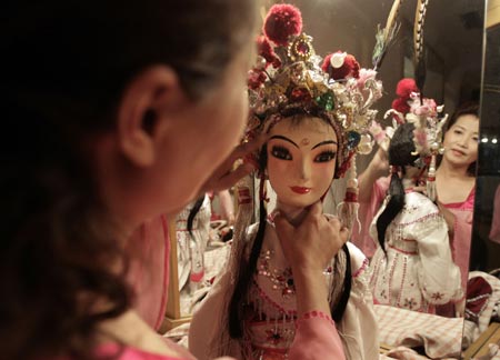 A performer prepares her puppet prior to a Sichuan Opera show at the Jingjiang Theatre in Chengdu, southwest China's Sichuan province May 25, 2007. Sichuan Opera, which is distinguished by the face-changing technique where performers change masks in quick succession with a wave of the hand or by turning around, is one of the oldest forms of Chinese opera.