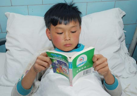 A student reads as he receives treatment after getting hurt during lightning at a hospital in Kaixian County, Southwest China's Chongqing Municipality, May 25, 2007. Seven children were killed and 39 were injured on Wednesday afternoon when lightning struck their three-room school house in the village of Xingye in Kaixian County. Six students with serious injuries are still hospitalized, Xinhua News Agency reported on Friday. [Xinhua]