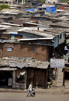 A man walks past slums in Dharavi, Asia's largest slum area, in Mumbai May 30, 2007. Authorities in Indias financial capital invited a global tender on Wednesday to tear down Asias biggest slum and replace it with gleaming new apartments, but the project is suspect in the eyes of most of it inhabitants. 