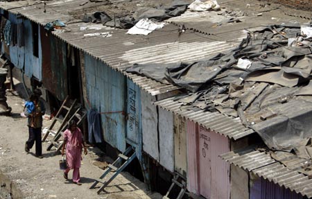 People walk past slums in Dharavi, Asia's largest slum area, in Mumbai May 30, 2007. Authorities in India's financial capital invited a global tender on Wednesday to tear down Asia's biggest slum and replace it with gleaming new apartments, but the project is suspect in the eyes of most of it inhabitants. 