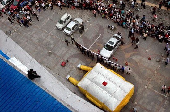 A man threatens to jump from the fifth floor as an airbag is placed on the ground to save him at a shopping center in Beijing, June 1, 2007. The man was the contractor for a decoration project in the shopping center and claimed that the center owed him and his employees 2 million yuan. Eight hours later, he was persuaded to leave the building and agreed to negotiate further with the shopping center. [Yi Yafei/The Beijing News]