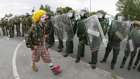 An anti-G8 protester dressed as a clown parades in front of German riot police during a demonstration for migration in Lichtenhagen, a suburb of the northern German city of Rostock June 4, 2007. 