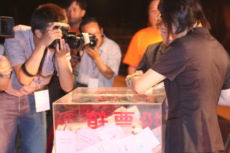Photographers take the picture as two notary officials seal the balloting boxes after a voting on the housing demolition and compensation policy at Jiuxianqiao sub-district in Chaoyang District of Beijing, June 9, 2007. Some 3,711 families, about 57% of the 5,473 families, cast their votes on Saturday, with 2,451 votes for and 1,228 votes against the demolition and compensation plan. Thirty-two votes were invalid. [Sun Yuqing/www.chinadaily.com.cn]