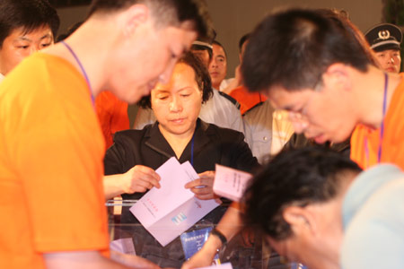 A notary official in black uniform and residents's representatives count votes after a voting on the housing demolition and compensation policy at Jiuxianqiao sub-district in Chaoyang District of Beijing, June 9, 2007. Some 3,711 families, about 57% of the 5,473 families, cast their votes on Saturday, with 2,451 votes for and 1,228 votes against the demolition and compensation plan. Thirty-two votes were invalid. 