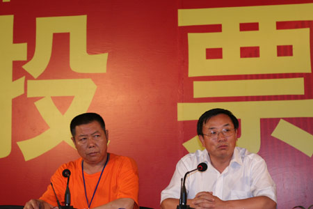 Ba Changrui [R] , deputy leader for the Jiuxianqiao Sub-district Office, delivers a closing speech on the vote as an official from the real estate company sits aside at Jiuxianqiao sub-district in Chaoyang District of Beijing, June 9, 2007. Some 3,711 families, about 57% of the 5,473 families, cast their votes on Saturday, with 2,451 votes for and 1,228 votes against the demolition and compensation plan. Thirty-two votes were invalid. 