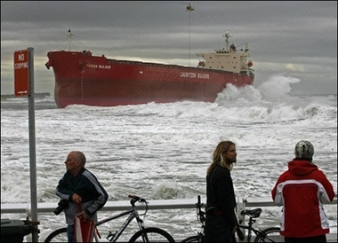 Locals watch a helicopter lower salvage equipment to the deck of the 30,000-tonne bulk coal carrier 'Pasha Bulker' which ran aground in wild seas off a beach in Newcastle, north of Sydney. Six people were confirmed dead and another two were missing as wild storms continued to lash Australia's east coast, smashing boats, flooding roads and cutting power to 200,000 homes.[AFP]