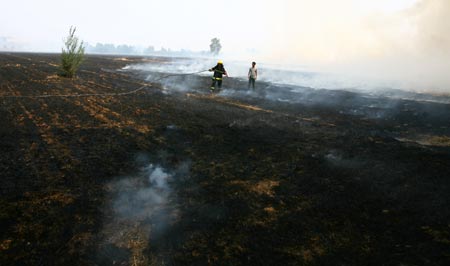 Chinese firemen try to extinguish a fire in a wheat field in Zhengzhou, Central China's Henan Province, June 12, 2007. A local official suspected that someone set fire on wheat straws near a road and the fire quickly spread to the field for the dry weather, Dahe Daily reported. The fire damaged the corn seedling in an area of 670,000 square meters and also shrouded nearby villages with heavy smoke.