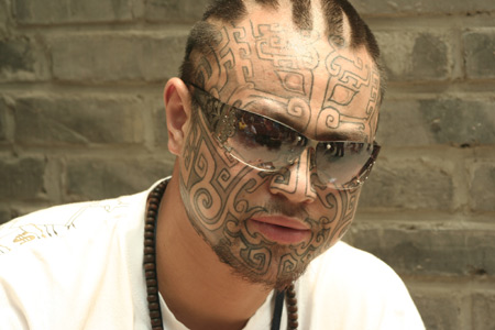 A man shows the designs on his face during the Tattoo Show Convention China 