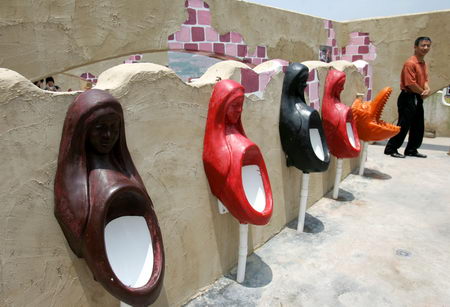 A man walks past urinals in different shapes on a wall in a public toilet in Southwest China's Chongqing Municipality, July 7, 2007. The disputed toilet features an Egyptian facade, soothing music and more than 1,000 toilets spread out over 30,000 square feet. Officials claimed the public bathroom the largest free one in the world. [Chen Yifeng/Chongqing Times]