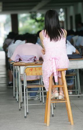 A teacher supervises as students take the examination at a hall in Dongguan University of Technology in Dongguan, South China's Guangdong Province, July 9, 2007. The university authority organized 1200 students to take the examination in a large hall to prevent exam fraud, Southern Metropolitan News Reported. [Fang Guangming/ Southern Metropolitan News]