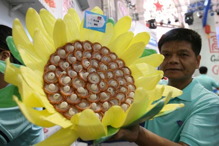 A worker shows a design made of condoms at the 4th China Reproductive Health New Technologies & Products Expo in Beijing July 11, 2007. Condoms of all shapes and sizes were on show at a Beijing fashion show on Wednesday featuring dresses, hats and even lollipops made of the said item.[newsphoto] 