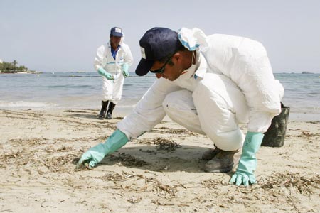 Workers clean up fuel oil at Figuerete's beach in Ibiza July 16, 2007. An oil slick from a ship that sank near the port of Ibiza has reached the waters of a nature reserve on the southern coast of the holiday island, a Spanish government minister said on Sunday.