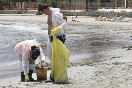 Workers clean up fuel oil on Talamanca beach in Ibiza July 15, 2007. An oil slick from a ship that sank near the port of Ibiza has reached the waters of a nature reserve on the southern coast of the holiday island, a Spanish government minister said on Sunday. 
