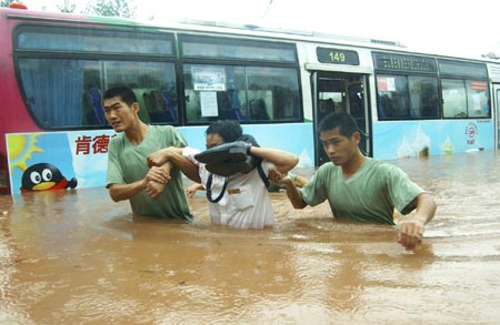 Chinese soldiers evacuate passengers from a bus stranded in flood after a heavy downpour in Southwest China's Chongqing Municipality, July 17, 2007. [Xinhua]