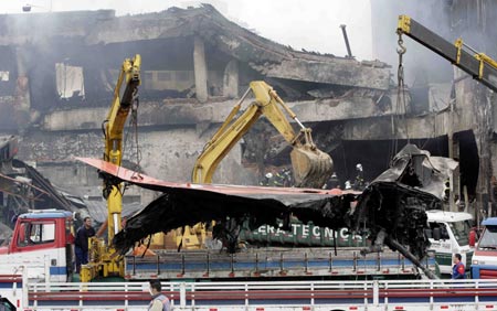 Workers lift onto a truck a section of a TAM airlines Airbus A320 that slid off the runway of Congonhas airport and into a building before it exploded in fire, in Sao Paulo July 18, 2007. Rescue workers hunted for bodies in the smoking wreckage of an airliner on Wednesday after it crashed at Brazil's busiest airport, killing up to 200 people in the country's worst air disaster. The terminal at Sao Paulo's Congonhas airport echoed with the shock and sorrow of survivors and relatives of the dead. 