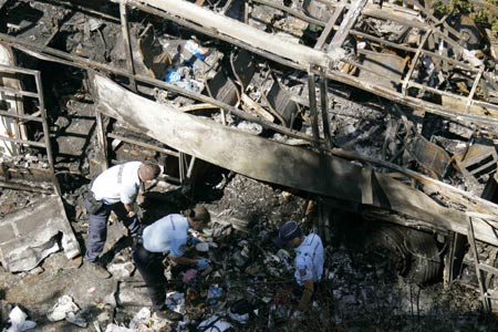 Rescue workers search wreckage of a coach carrying Polish pilgrims plunged down a hillside and burst into flames at Vizille near the southeastern French city of Grenoble, July 22, 2007. At least 24 died and as many seriously injured in the vehicle which crashed through a barrier after a steep hill and came to rest on the banks of the river Romanche and burst into flames. 