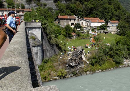 Police overlook the scene where a coach carrying Polish pilgrims plunged down a hillside and burst into flames at Vizille near the southeastern French city of Grenoble, July 22, 2007. At least 24 died and as many seriously injured in the vehicle which crashed through a barrier after a steep hill and came to rest on the banks of the river Romanche and burst into flames.