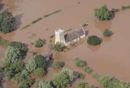 An aerial view shows flood water surrounding a church in Tirley near Tewkesbury, in central England July 22, 2007. Torrential rain caused flash floods and brought transport chaos, the Highways Agency said on Saturday. As many as 2,000 people had to be taken to emergency centres in the Cotswolds, one of England's most picturesque regions. 