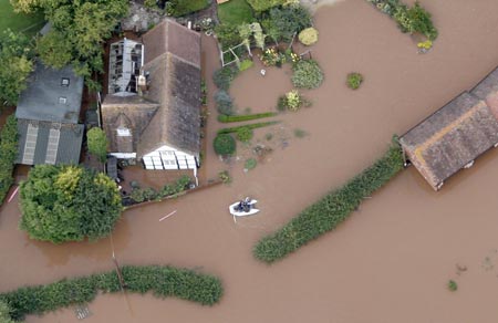 A boat moves through flood water around Upton upon Severn, in central England July 22, 2007. Torrential rain caused flash floods and brought transport chaos, the Highways Agency said on Saturday. As many as 2,000 people had to be taken to emergency centres in the Cotswolds, one of England's most picturesque regions. 