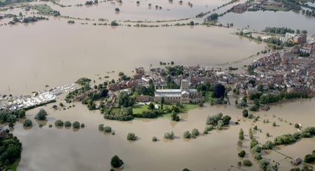 An aerial view shows flood water surrounding Tewkesbury Abbey, in central England July 22, 2007. Torrential rain caused flash floods and brought transport chaos, the Highways Agency said on Saturday. As many as 2,000 people had to be taken to emergency centres in the Cotswolds, one of England's most picturesque regions. 
