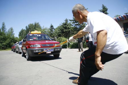 Ji Fengshan, 56, drags four cars with a finger as he hangs himself to a horizontal bar at a park in Harbin,Northeast China's Heilongjiang Province, July 23, 2007. [newsphoto]