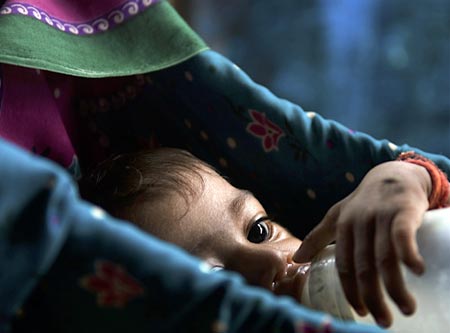 Seven-month-old Rohini who is suffering from malnutrition drinks milk inside a hut in Mumbai July 25, 2007. Rohini and her twin brother Rohit who come from a tribal family have been declared malnourished by a team of the city's civic administration doctors, local media reported. India, home to millions of underfed children despite its flourishing economy, will have eradicated malnutrition by 2015, the country's health minister said. A government survey released this year however found that 46 percent of children under the age of three years were undernourished.