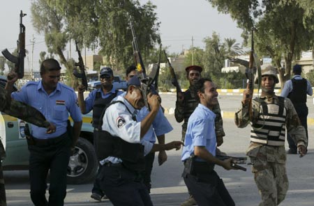 Iraqi soldiers and policemen hold their weapons as they celebrate the victory of Iraq's soccer team over South Korea during the semi-final of 2007 AFC Asian Cup soccer tournament, at a check[point in Baghdad July 25, 2007. 