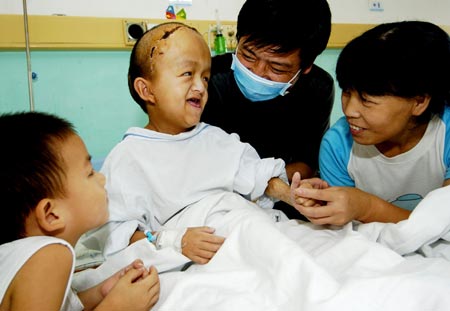 Chinese boy Liu Jing (2nd R) talks with his parents and younger brother as he recovers from a surgery to reconstruct his deformed skull at a hospital in Xiamen, East China's Fujian Province, August 2, 2007. Liu Jing, 9, suffering from hydrocephalus at his birth and later the deformed skull, received a 13-hour surgery on July 15, 2007. [Xinhua]