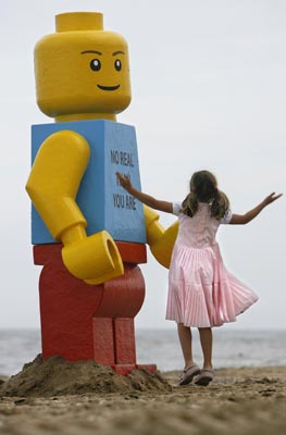 A girl plays near a giant smiling Lego man that was fished out of the sea in the Dutch resort of Zandvoort August 7, 2007. Workers at a drinks stall rescued the 2.5-metre (8-foot) tall model with a yellow head and blue torso. The toy was later placed in front of the drinks stall. 